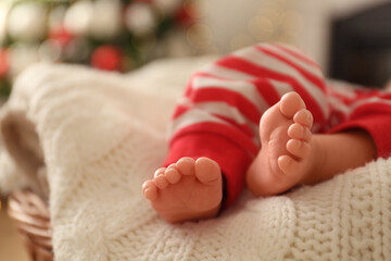cute little baby on knitted blanket in room with christmas tree, closeup