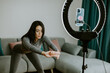 © shevtsovy - Virtual online fitness. Woman virtual workout at home living room. Fitness stretching exercises online women at home with smartphone. Attractive Woman personal trainer coach recording on camera new