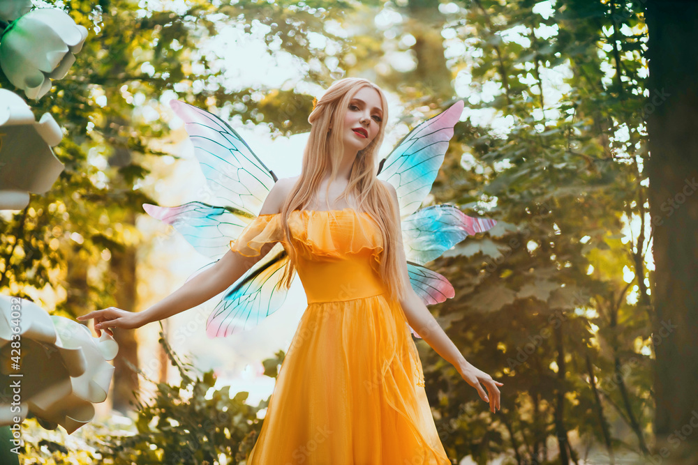 Portrait fantasy woman blonde forest fairy. Elf girl fashion model in bright yellow dress, butterfly wings. Pixie walks in summer nature. Green spring tree, wood, sun light magic radiance. Long hair Stock Portrait fantasy woman blonde forest fairy. Elf girl fashion model in bright yellow dress, butterfly wings. Pixie walks in summer nature. Green spring tree, wood, sun light magic radiance. Long hair Stock