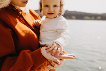 Mother and child spending time together outdoors. Mother holding little daughter's hand on her palm.