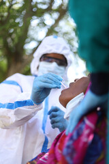 Vertical shot of a healthcare worker taking a coronavirus test from an old Indian woman