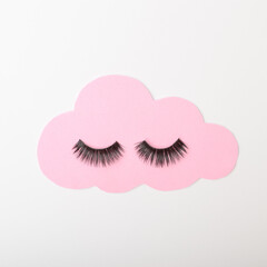 A pastel pink cloud with black lashes on a white background. Cloud connect  still life inspiration. Flat lay frame.