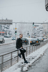 Wall Mural - Vertical shot of a caucasian young male posing outdoors in a snowy city