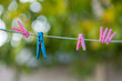 pink and blue clothespins hanging on a clothesline, focus on blue clothespin, shallow depth of field, close-up.