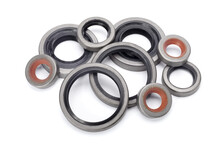 Pile Of Different Rubber Reinforced Oil Seals For Shafts And For Car Motor Engines Isolated On White Background. Cuffs For Prevent Liquid Leak. Car Parts.