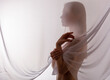 The silhouette of a beautiful nude woman behind a transparent fabric.