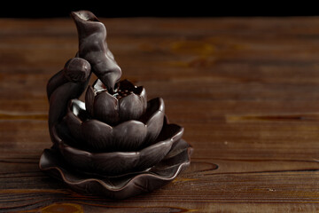 Ceramic backflow incense burner in the form of lotus flower. Incense cones holder. Dark mystic concept.