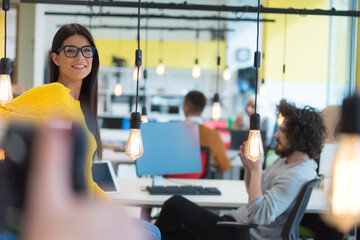 Portrait of young beautiful happy casual businesswoman standing with laptop at her workplace inside modern co working space.