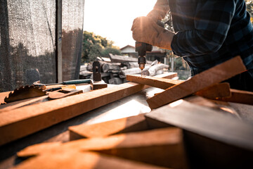 Close-up view A carpenter using a drilling tool or an electric screwdriver is working at home on the wooden floor. Ideas for home improvement and extension.