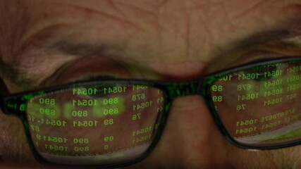 The Programmer with Wlasses in front of the Display. Reflection of the Monitor with a Numeric Code.