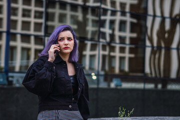 Wall Mural - Upset European female with purple hair talking on her phone outdoors