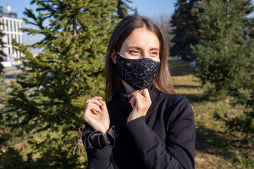 Poster - Shallow focus shot of a Caucasian woman wearing a white mask and posing in the park