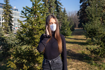 Poster - Shallow focus shot of a Caucasian woman wearing a white mask and posing in the park