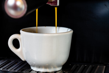 Poster - Cup of espresso while the cup is filling in a coffee machine