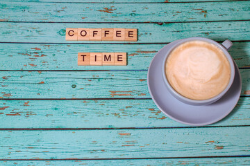 Top view coffee time lettering of alphabet wooden blocks on blue wooden background