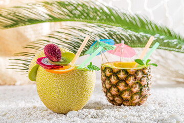 Wall Mural - Tropical cocktails in fruits on pebbles. Drink for summer heat.