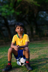 Wall Mural - Young boy Sitting in the ground with football 