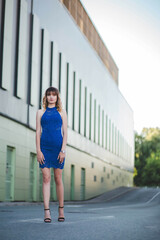 Sticker - Vertical shot of a blonde Caucasian in heels and blue dress standing on an empty street