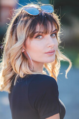 Poster - Shallow focus shot of a confident Caucasian female in sunglasses posing for the camera in a park