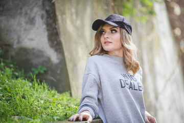 Wall Mural - Attractive blonde hair Caucasian female in a black cap looking around and posing at camera