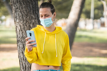 Poster - Vertical shot of a white Caucasian woman playing with her phone in the park