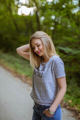 Wall Mural - Vertical shot of a young blonde female posing on the road near the forest