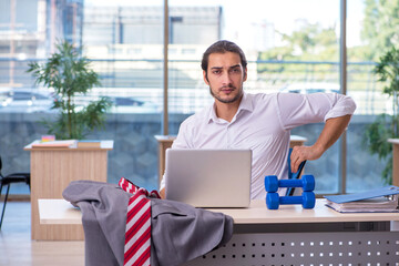 Young male employee doing sport exercises in the office