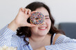 © Bangkok Click Studio - Closeup shot of delicious chocolate donut decorated with colorful sugar sprinkles in Asian young happy beautiful long black hair oversized fat female model hand who smile look through doughnut hole