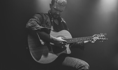 Wall Mural - Guitarist playing acoustic guitar in a dark smoky room.