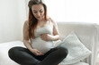 © puhimec - Young pregnant woman is sitting on the sofa at home.