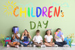© Pixel-Shot - Little children with copybooks sitting on floor near color wall. International Children's Day celebration