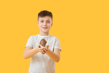 Canvas Print - Cute little boy with chocolate Easter egg on color background