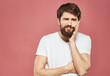 © SHOTPRIME STUDIO - Guy touches his face with his hands on a pink background cropped view