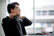 © Bangkok Click Studio - Asian business man wearing eyeglasses, formal black suit with necktie, getting tired and pain on his neck while taking rest after work and sitting in workplace. Office Syndrome and Health concept