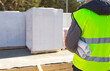 © Ольга Симонова - The project architect's back is on the construction site of a house with the foundation laid and the blocks delivered. Construction worker in a protective yellow helmet and a signal vest. Mock up