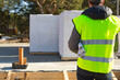 © Ольга Симонова - The project architect's back is on the construction site of a house with the foundation laid and the blocks delivered. Construction worker in a protective yellow helmet and a signal vest. Mock up
