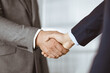 © rogerphoto - Business people in office suits standing and shaking hands, close-up. Business communication concept. Handshake and marketing