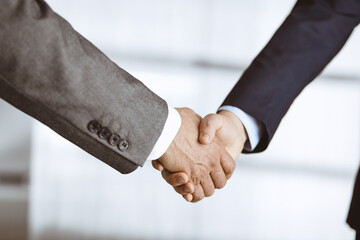 Business people in office suits standing and shaking hands, close-up. Business communication concept. Handshake and marketing