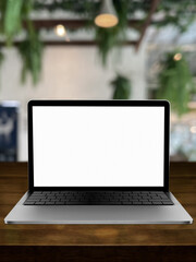 Blank screen laptop computer on wood table top with coffee shop bokeh background.