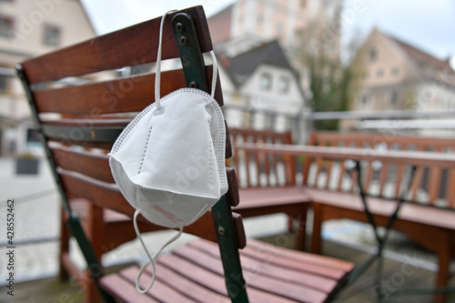 Corona crisis - lockdown - FFP2 mask hangs on a chair in an empty beer garden in Steyr, Austria, Europe