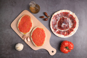 Wall Mural - Breakfast of bread toasts with acorn-fed Iberian ham, tomato, garlic and olive oil (tumaca bread) on dark gray background