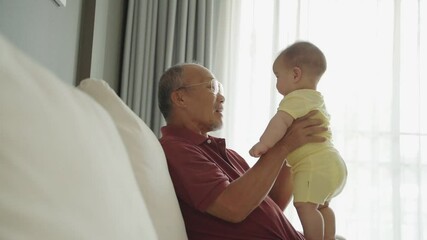 Wall Mural - Smiling Asian Grandfather playing holding with his cute baby boy.