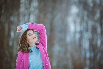 Poster - Shallow focus shot of a beautiful Caucasian woman with glasses posing in the snowy forest