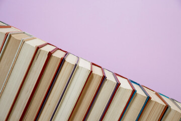 Composition with vintage old hardback books, diary, fanned pages on wooden deck table and colored background. Books stacking. Back to school. Copy Space. Education background.