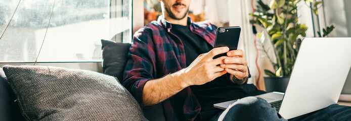 Young man with laptop and smartphone at home. Freelancer. Concept of remote work or study.