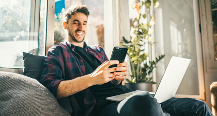 Young man with laptop and smartphone at home. Freelancer. Concept of remote work or study.