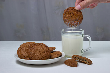 Oatmeal cookies dipped in a glass of milk on a white background. Diet food. Light breakfast