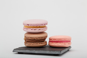 Wall Mural - Colorful macaroons on grey mat on white background. Sweet bakery, copy space.