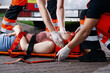Professional medical rescuer bending over a car accident victim lying on a stretcher