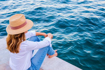 Wall Mural - Woman wearing casual clothes while relaxing and looking at the sea